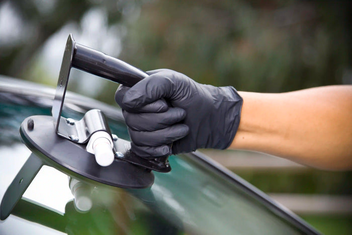 Close-up of technician using suction tool during professional windshield replacement at Tire Discounters auto glass service center.