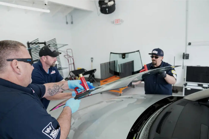Technicians replacing windshield with precision tools at Tire Discounters, highlighting expert auto glass repair and replacement services.