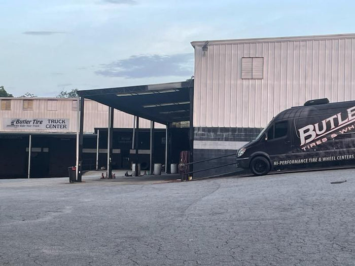 Butler Tire Discounters Commercial building with a Butler van parked outside and truck service bays under a covered awning.
