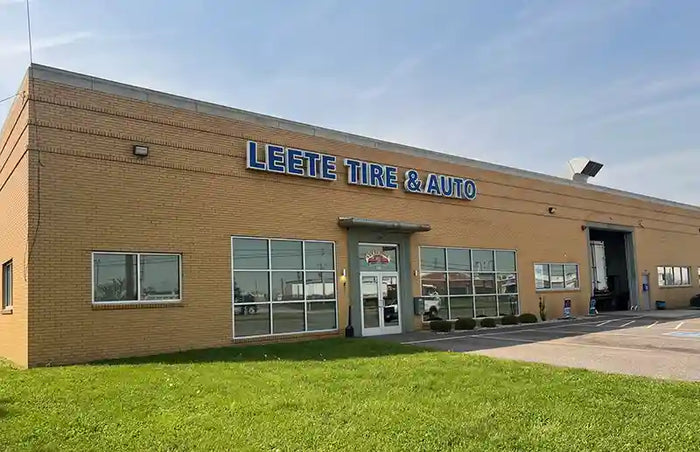 Leete Tire Discounters Commercial building with brick exterior, front entrance, and service garage bay on a clear day.