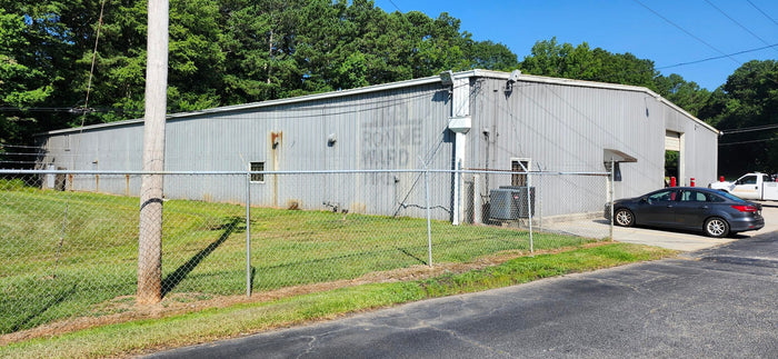 Tire Discounters Commercial building with a gray metal exterior, chain-link fence, and parked vehicles in front.