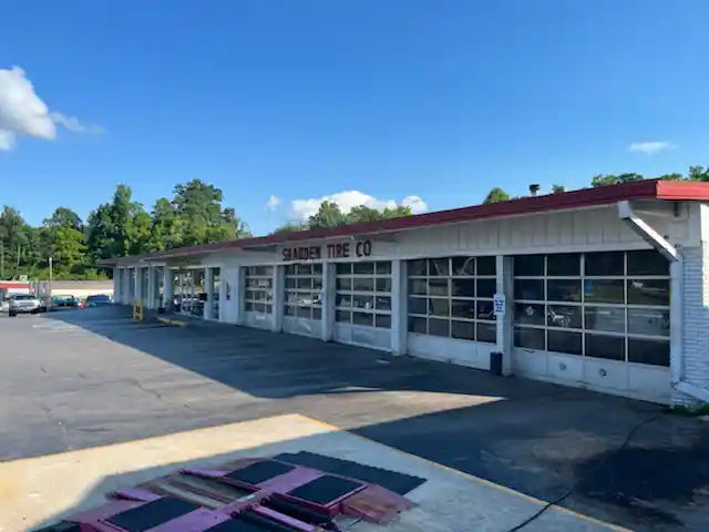 Shadden Tire Discounters Commercial building with white exterior, red trim, and multiple garage bays under a clear blue sky.