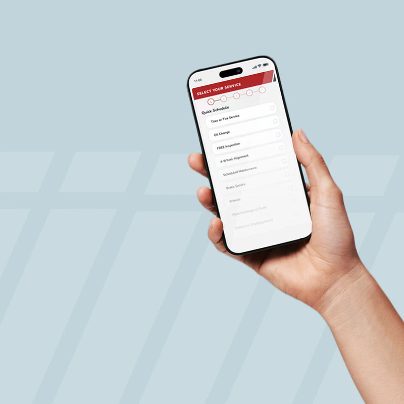 Hand holding smartphone with Tire Discounters online service scheduling app.