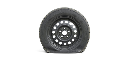 Flat black steel wheel with deflated all-season tire, showing loss of air pressure and compressed sidewall on white background.