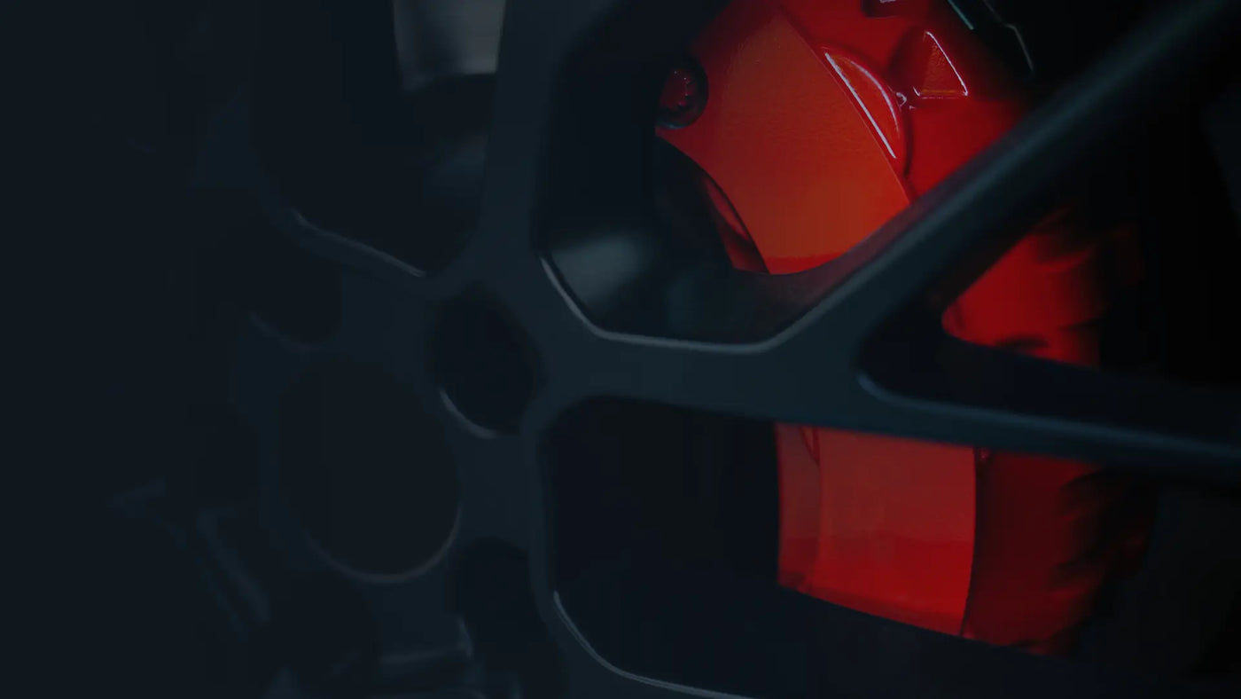 Close-up of red brake caliper behind custom black alloy wheel | Tire installation & brake service at Tire Discounters