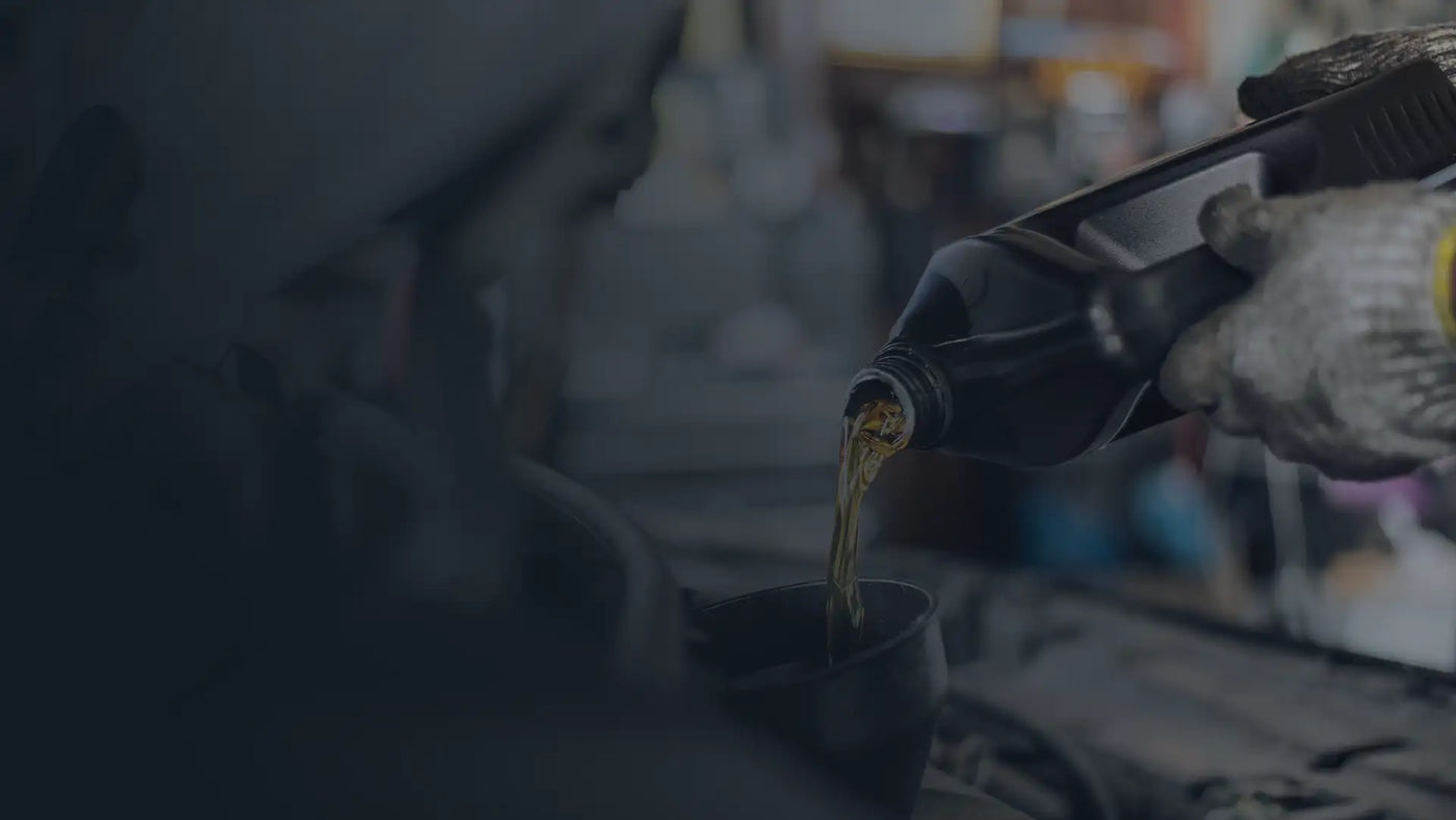 Person pouring oil from a bottle into a container with a blurred background