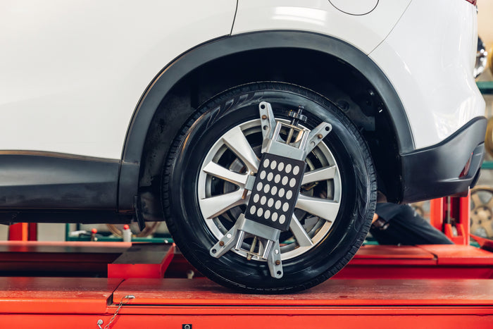 Vehicle wheel on alignment machine with sensors attached for precise wheel alignment service in an auto repair shop.