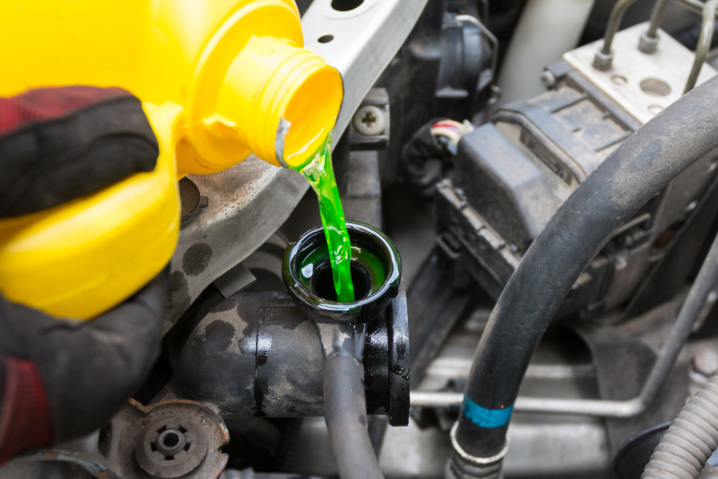Technician pouring green coolant into radiator — expert radiator flush and coolant service available at Tire Discounters.