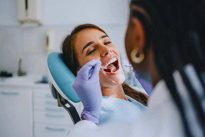 Young woman receiving dental checkup from hygienist in clinic, highlighting preventative oral care and professional dental services.