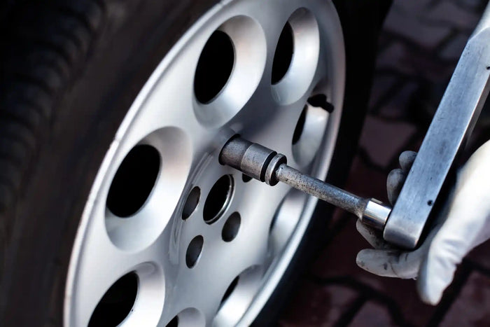 Close-up of a tire being worked on with a torque wrench, tightening down the lug nuts.
