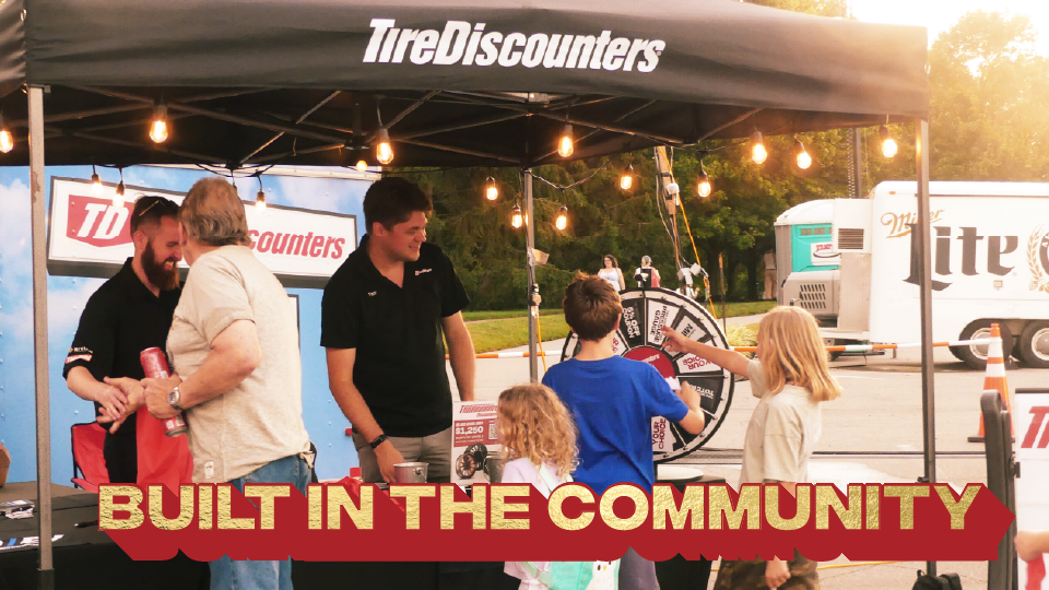Tire Discounters employee with children spinning prize wheel