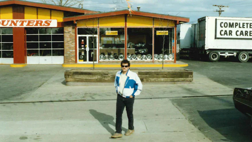 Photo from 90s of founder Chip Wood wearing a tracksuit in front of Tire Discounters