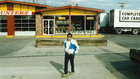 Photo from 90s of founder Chip Wood wearing a tracksuit in front of Tire Discounters