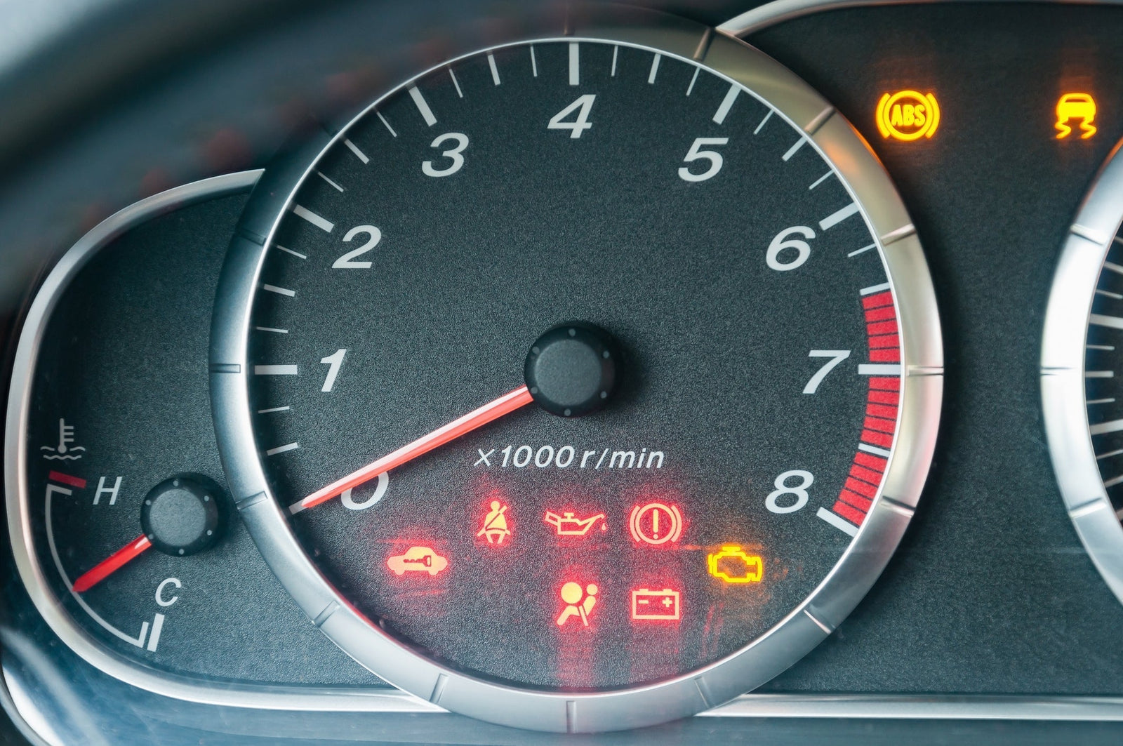 Car dashboard illuminated with multiple warning lights, including check engine, oil pressure, ABS, battery, and brake indicators
