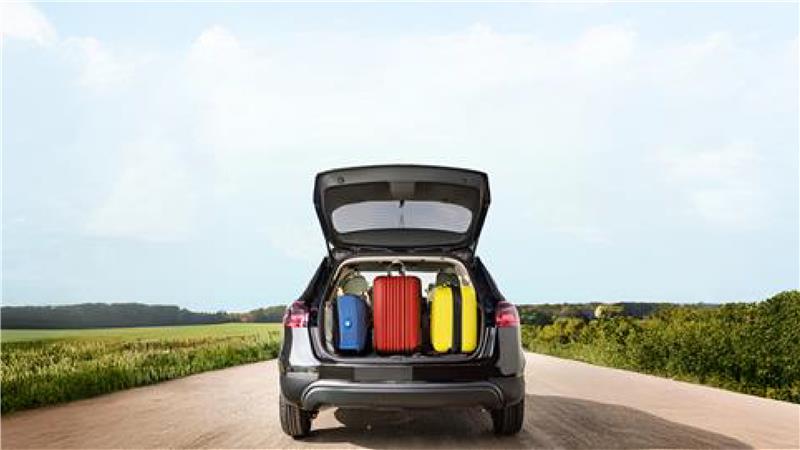 Car parked on an open road with trunk full of luggage, ready for a spring break road trip
