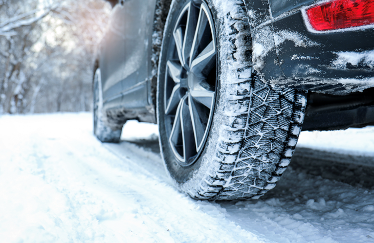 Winter tire with deep tread gripping a snowy road, showing traction and control in icy winter driving conditions