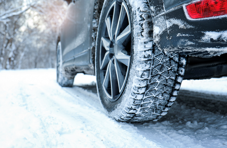 Winter tire with deep tread gripping a snowy road, showing traction and control in icy winter driving conditions