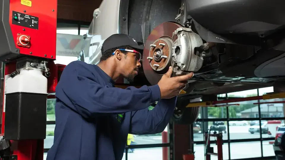 ASE-certified technician inspecting brake rotors and calipers during a free brake inspection at Tire Discounters service center
