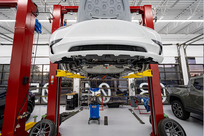 Tesla Model S on lift for battery replacement service at Tire Discounters EV service bay, wheels removed for maintenance.