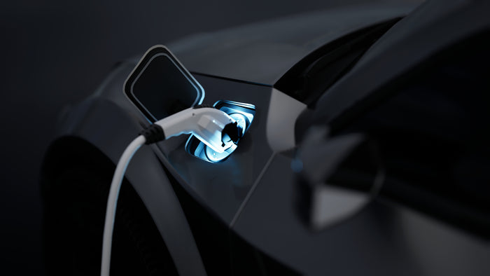 Electric vehicle charging at night with glowing blue port, showcasing EV service or battery charging station.