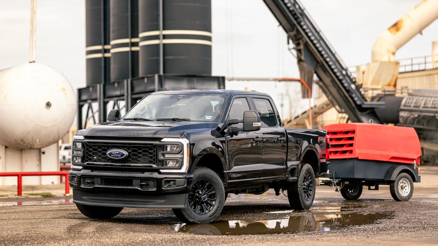 Black Ford truck with a red trailer in an industrial setting