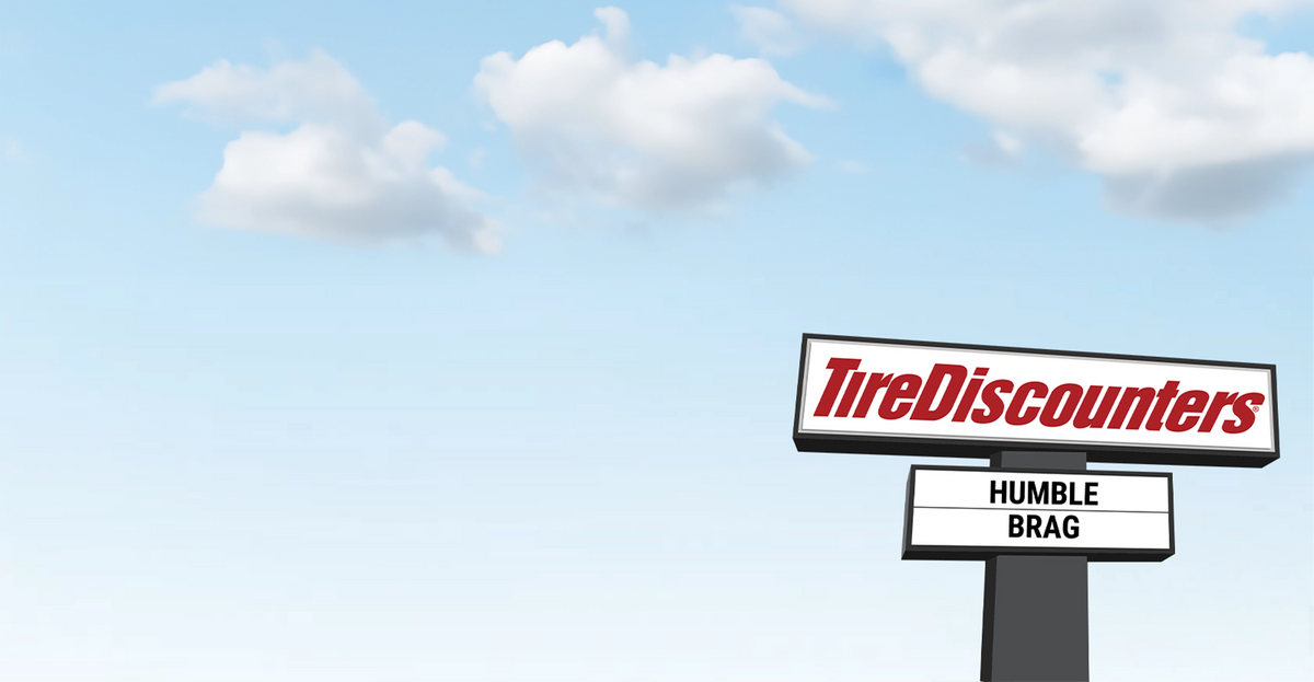 Illustration of a Tire Discounters roadside sign against a blue sky with clouds, featuring a humorous message that reads “HUMBLE BRAG.”