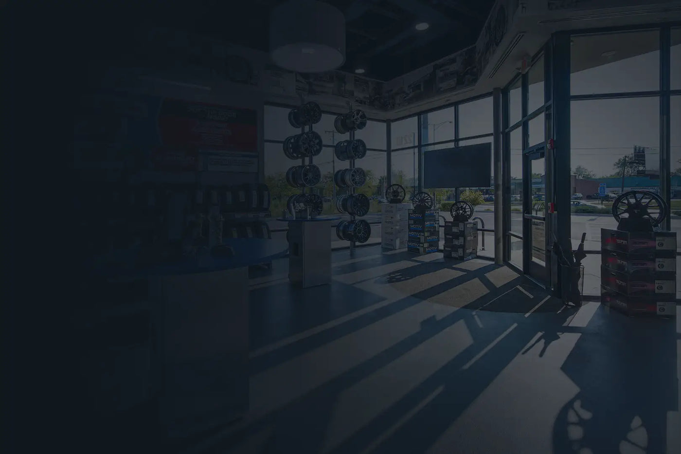 Tire Discounters showroom with display wheels, tires, and natural light streaming through large glass windows at the store entrance.