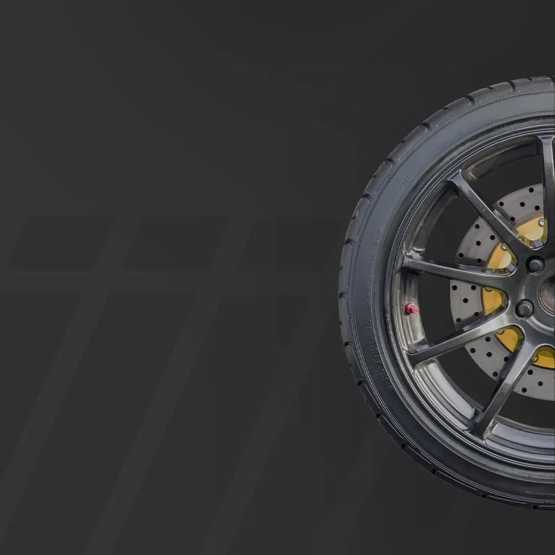 Close-up of a performance car tire and black alloy wheel with brake rotor, set against a dark textured background.