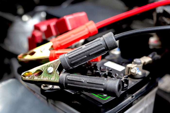 Close-up of jumper cables connected to a car battery for a jump-start.