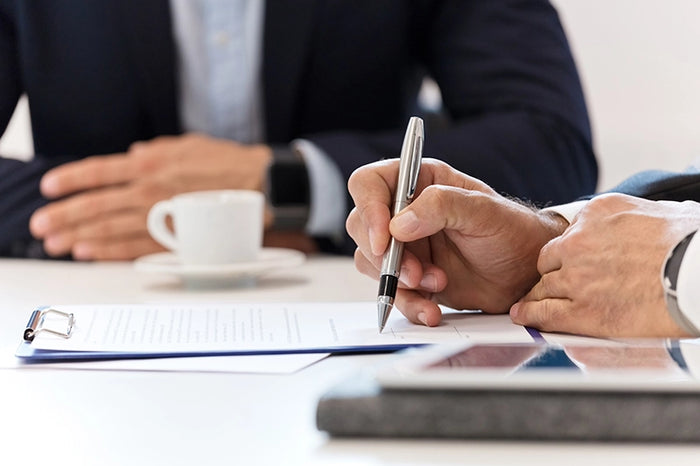 Close-up of business professionals signing a contract, highlighting corporate agreements, partnerships, and legal documentation.