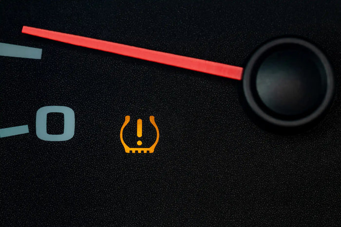 Tire pressure warning light illuminated on vehicle dashboard, indicating low tire pressure or TPMS system issue.